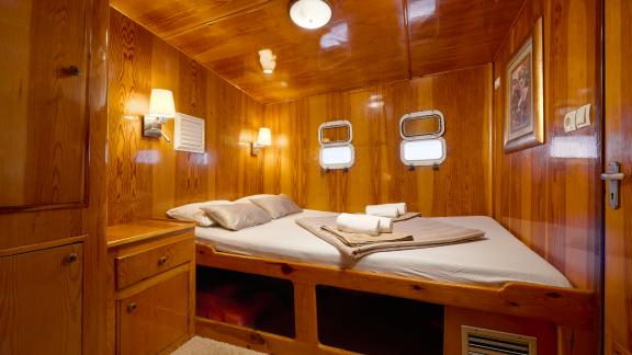 A cosy cabin on the Gulet Linda with a double bed and warm wooden walls.